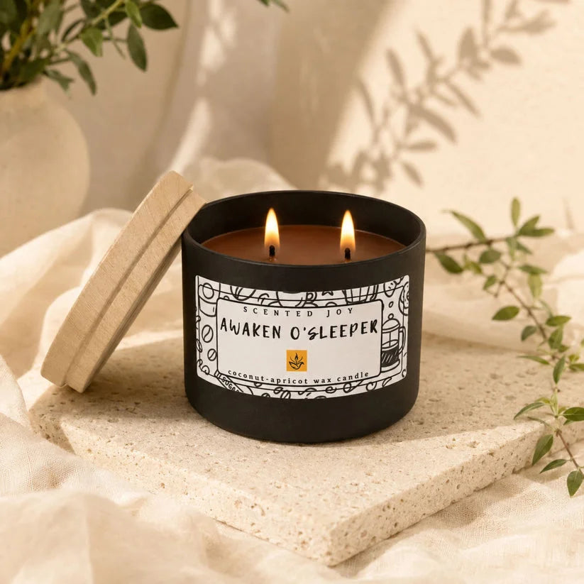 Scented Joy Awaken O'Sleeper coconut-apricot wax candle with two lit wicks and wooden lid.