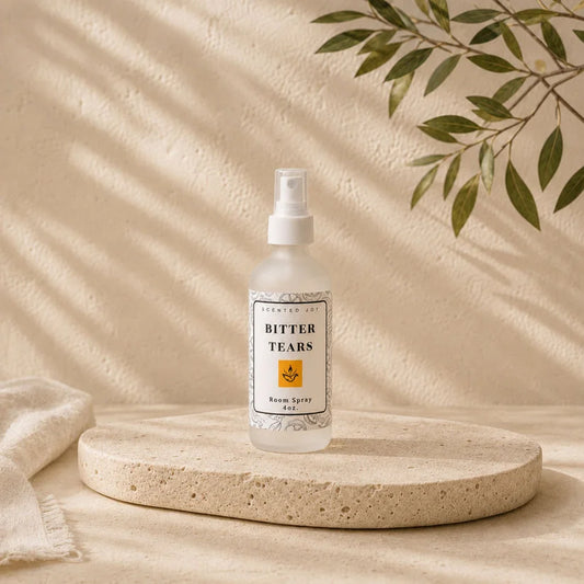 Bitter Tears room spray by Scented Joy on a stone pedestal with aesthetic leaf shadows.