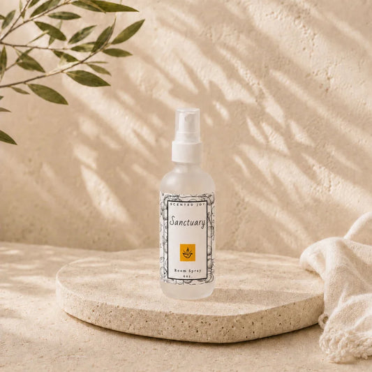 Scented Joy Sanctuary Room Spray in a frosted bottle on a stone tray with leaf shadows